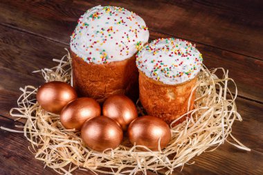 Yuvadaki Paskalya altın yumurtaları, bayram hazırlıkları. Koyu renkli arka planda yuvadaki altın yumurtalar.