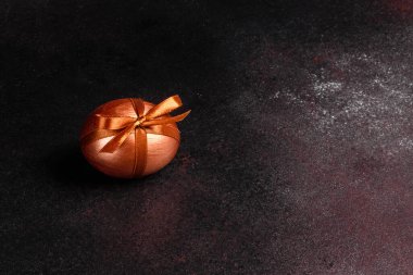 Karanlık ahşap bir arka planda hediye bandıyla Paskalya yumurtası. Tatil için hazırlık
