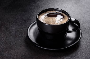 Güne neşeyle başlamak için bir fincan taze kokulu sabah kahvesi. Koyu kahve masasında güzel bir kahve fincanı.