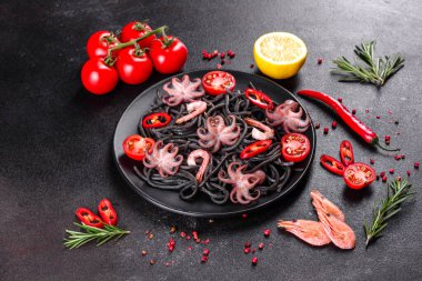 Siyah zemin üzerinde karides, ahtapot ve midye olan siyah deniz ürünleri makarnası. Akdeniz gurme yemekleri. Siyah ahtapot kaplı siyah makarna.