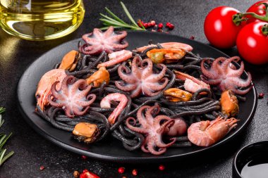 Siyah zemin üzerinde karides, ahtapot ve midye olan siyah deniz ürünleri makarnası. Akdeniz gurme yemekleri. Siyah ahtapot kaplı siyah makarna.