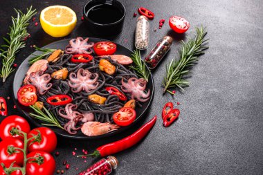 Siyah zemin üzerinde karides, ahtapot ve midye olan siyah deniz ürünleri makarnası. Akdeniz gurme yemekleri. Siyah ahtapot kaplı siyah makarna.