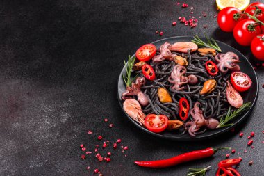 Siyah zemin üzerinde karides, ahtapot ve midye olan siyah deniz ürünleri makarnası. Akdeniz gurme yemekleri. Siyah ahtapot kaplı siyah makarna.