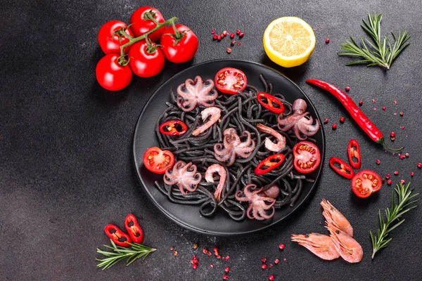 Siyah zemin üzerinde karides, ahtapot ve midye olan siyah deniz ürünleri makarnası. Akdeniz gurme yemekleri. Siyah ahtapot kaplı siyah makarna.