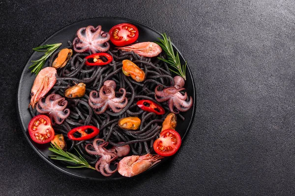 Black seafood pasta with shrimp, octopus and mussels on black background. Mediterranean gourmet food. Black pasta with octopus on a black stone plate