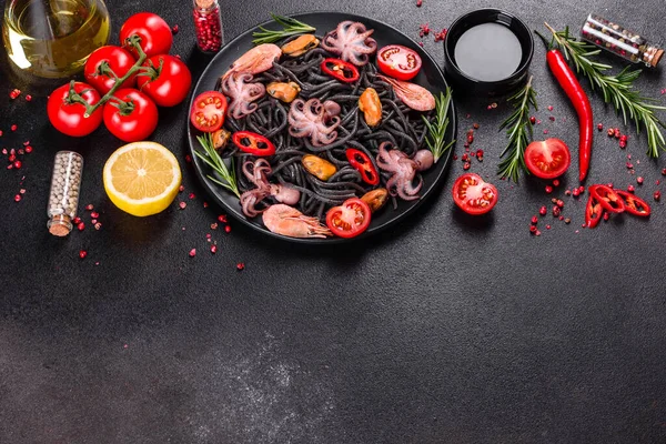 Black seafood pasta with shrimp, octopus and mussels on black background. Mediterranean gourmet food. Black pasta with octopus on a black stone plate