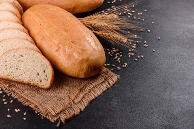 Kahverengi beton arka planda taze pişmiş beyaz ekmek. Koyu arkaplanda taze pişmiş geleneksel ekmek.
