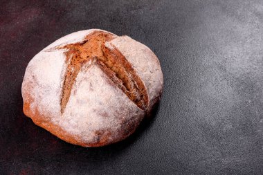Kahverengi bir arka planda taze pişmiş kahverengi ekmek. Koyu arkaplanda taze pişmiş geleneksel ekmek.
