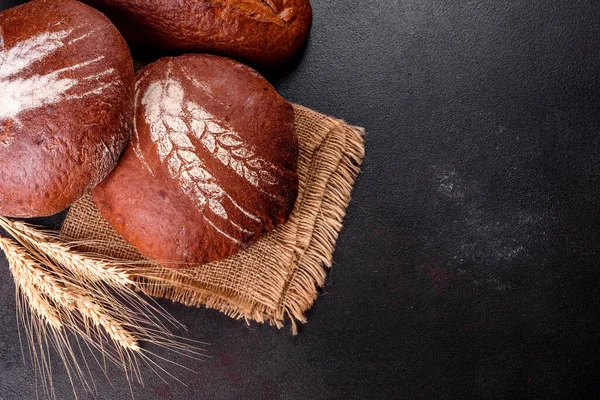 Fresh baked brown bread on a brown concrete background. Freshly baked traditional bread on a dark background.