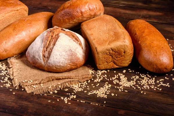 Fresh baked brown bread on a brown concrete background. Freshly baked traditional bread on a dark background