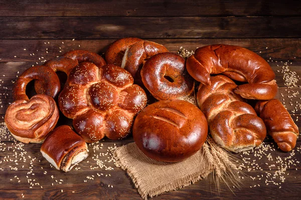 Composition of fresh baked sweet buns with poppy and jam. Sweet baking laid out as a composition on a wooden table