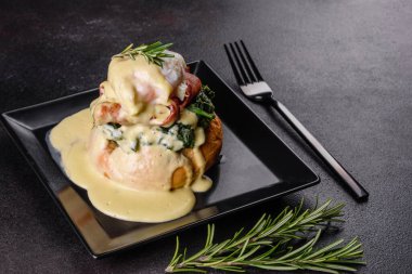 Benedict yumurtaları ya da Floransa usulü yumurtalar kafede siyah bir tabakta. Kızarmış İngiliz keki üzerine yumurtalı Benedict.