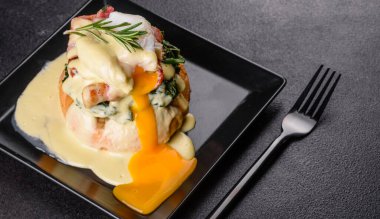 Benedict yumurtaları ya da Floransa usulü yumurtalar kafede siyah bir tabakta. Kızarmış İngiliz keki üzerine yumurtalı Benedict.