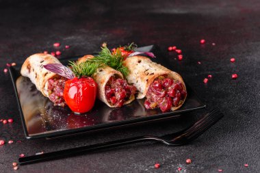 Lezzetli taze et tartartarı ve siyah bir tabakta siyah bir arka planda kızarmış ekmek.