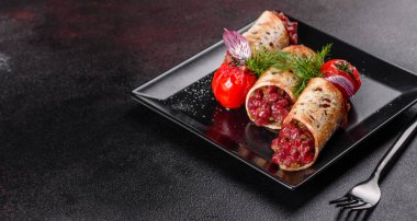 Lezzetli taze et tartartarı ve siyah bir tabakta siyah bir arka planda kızarmış ekmek.