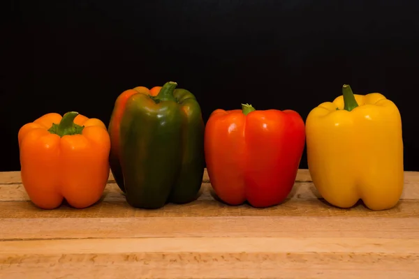 Kleurrijke paprika's op houten tafel — Stockfoto