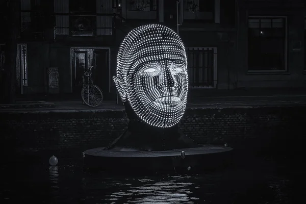 Floating head made of lights in an Amsterdam canal. — Stock Photo, Image