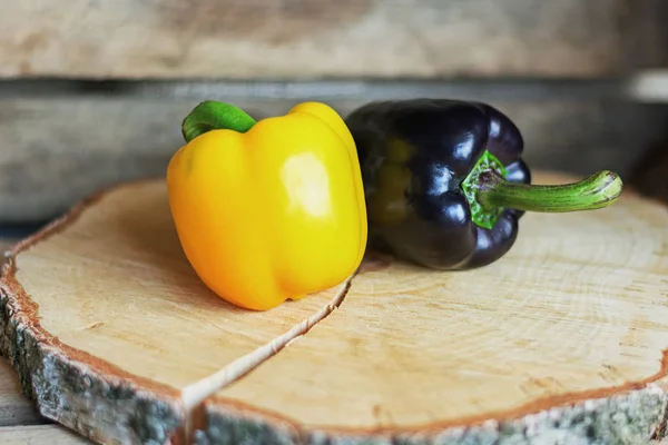 Black and yellow paprika's and on a disk of birch wood