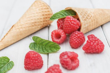 Koniler, ahududu ve bir dal yaymak üzerinde beyaz masa üstü nane