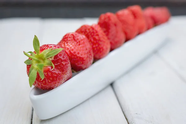 Olivenboot gefüllt mit Erdbeeren auf einem Holztisch — Stockfoto