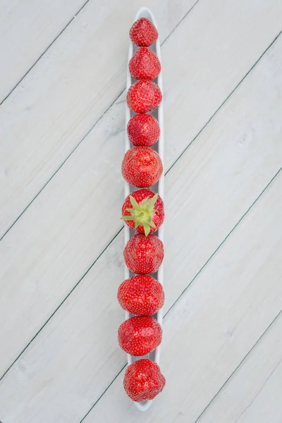 Olive boat filled with strawberries on a wooden table — Stock Photo, Image