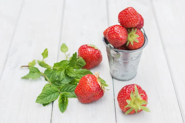 Small metal bucket filled with strawberries and a sprig of mint. — Stock Photo, Image