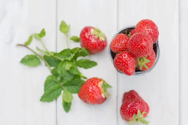 Kleiner Metalleimer gefüllt mit Erdbeeren und einem Zweig Minze. — Stockfoto