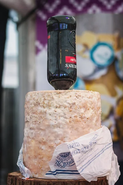 Botella de oporto pegada en un queso stilton exhibido en la comida f — Foto de Stock