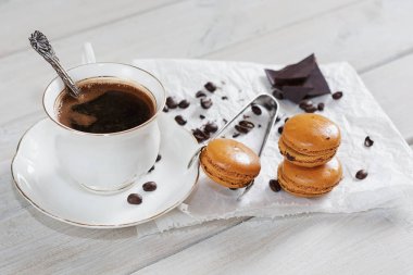 Gevşek kahve çekirdekleri ve kahve aromalı macarons ile beyaz bir peçeteye sunulan kahve çikolata eseriyle dekore