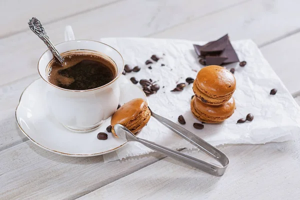 Gevşek kahve çekirdekleri ve kahve aromalı macarons ile beyaz bir peçeteye sunulan kahve çikolata eseriyle dekore.