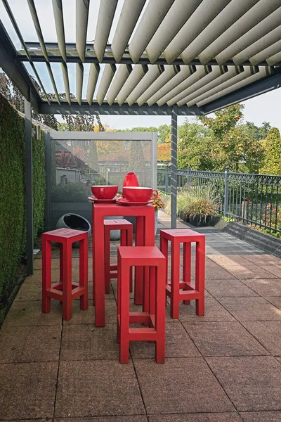 Υψηλή κόκκινο τραπέζι που περιβάλλεται από κόκκινο κάθισμα σκαμπό στο κιόσκι — Φωτογραφία Αρχείου