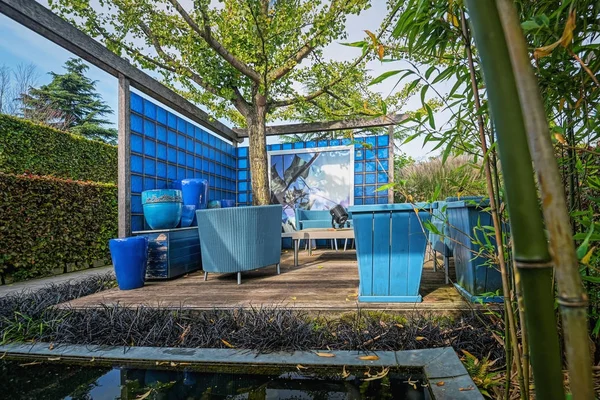 Ωραία διακοσμημένα γωνιά στον κήπο με ένα μπλε γυάλινο τοίχο στο παρασκήνιο — Φωτογραφία Αρχείου