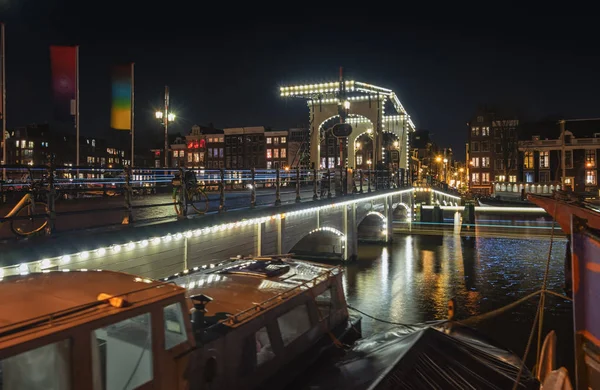 A Magere-híd az Amstel-folyó mellett, a háttérben a jellegzetes csatorna épülete Amszterdam központjában — Stock Fotó
