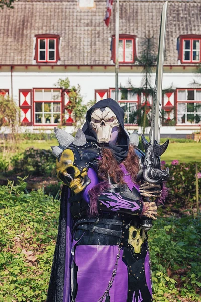 Kötü adam kafatası maskesi ve büyük kılıç Elf fantezi Fuarı süresince poz veriyor