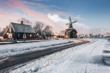 Hollanda 'daki De Zaan nehri kıyısındaki Zaans Schans' taki küçük değirmen ve tipik Zaanse evleri.
