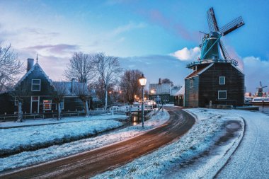 Hollanda 'daki De Zaan nehri kıyısındaki Zaans Schans' taki küçük değirmen ve tipik Zaanse evleri.