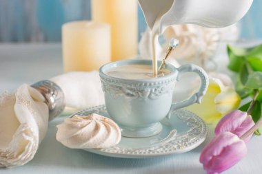 Tulip Eflatun ve beyaz peçete ahşap zemin üzerine ışık mavi Çin Kupası kahve ile süt dökme.