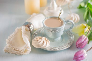 Tulip Eflatun ve beyaz peçete ahşap zemin üzerine açık mavi Çin kupada sütlü kahve.