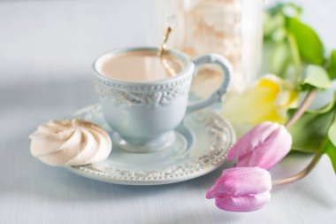 Tulip Eflatun ve beyaz peçete ahşap zemin üzerine açık mavi Çin kupada sütlü kahve.