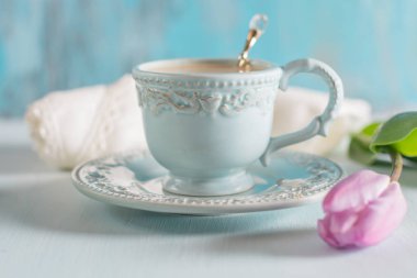 Tulip Eflatun ve beyaz peçete ahşap zemin üzerine açık mavi Çin kupada sütlü kahve.