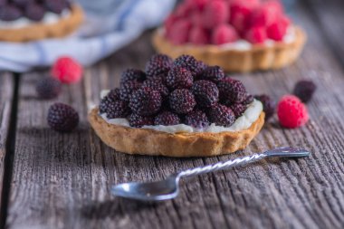 Böğürtlen mini tart gümüş kaşık ahşap tablo.