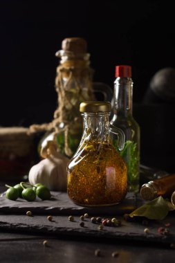 Testiler siyah bir taş gemide baharat, sarımsak ve zeytin çevrili sızma zeytinyağı ile. Seçici odak. Sağlıklı doğal gıda kavramı. Düşük anahtar,