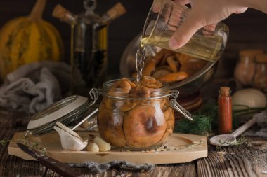 Bir cam tutarak ve Marine mantar kavanoza bir tuzlu su dökme kadın el ahşap bir masaya yerleştirilir. Hazırlıklar mutfakta. Pişirme işlemi.