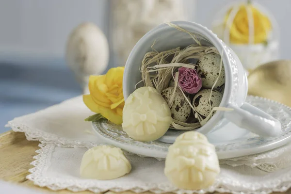 Paskalya yumurtaları ve beyaz peçete, Vintage aqua mavi ahşap arka plan, sığ odak Kupası closeup çikolata el yapımı şekerler.