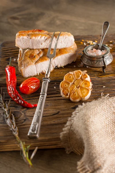 Izgara domuz etli domates ve sarımsak ahşap tahta üzerinde. 