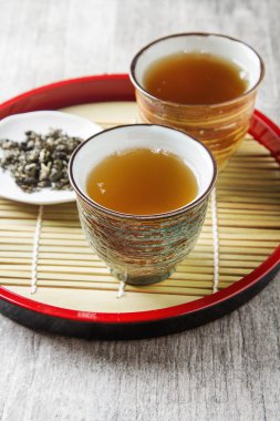 Seramik kupa yeşil çay ve lepistkami gül ile. Koyu arka plan