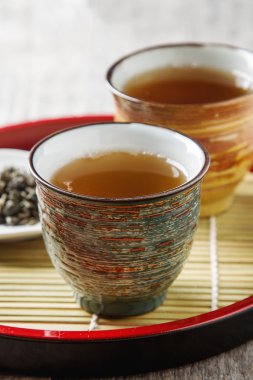 Seramik kupa yeşil çay ve lepistkami gül ile. Koyu arka plan