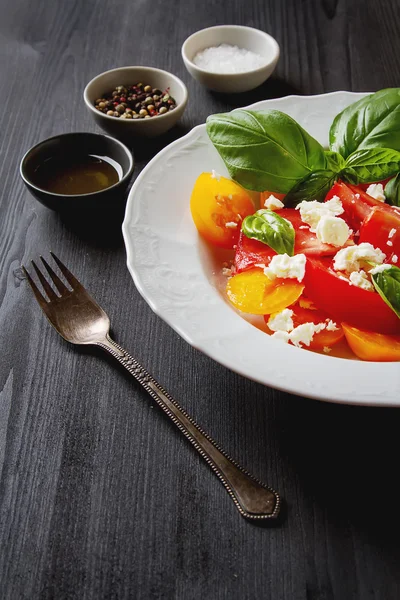 Insalata di pomodori maturi con basilico e formaggio feta su terale bianco — Foto Stock