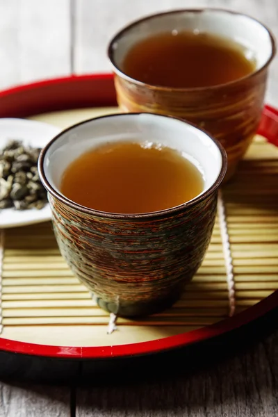 Tazza in ceramica con tè verde e rose lepistkami. Sfondo scuro — Foto Stock