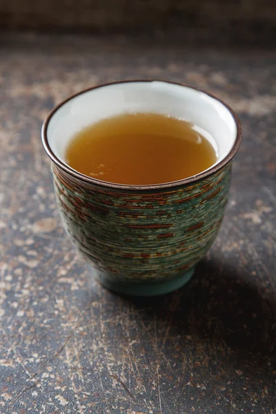 Ceramic mug with green tea and lepistkami roses. Dark background — Stock Photo, Image